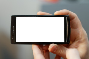 Close up of a mobile phone with a touch screen. Focus is on the phone with small DOF.